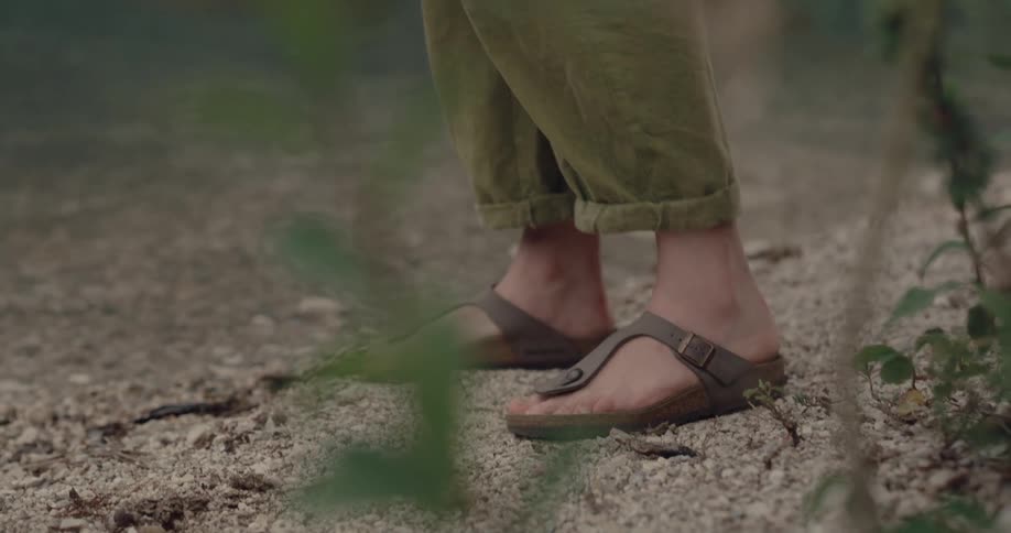 Feet in sandals move back a bit as the clear river water laps at the shore