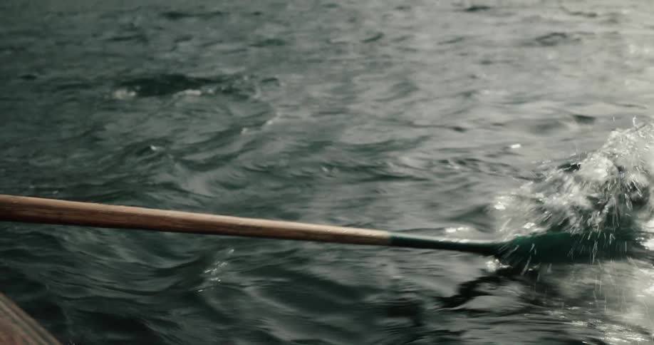 Man and woman on a date in a wooden canoe in the middle of the lake while shes playing a mini guitar and hes rowing
