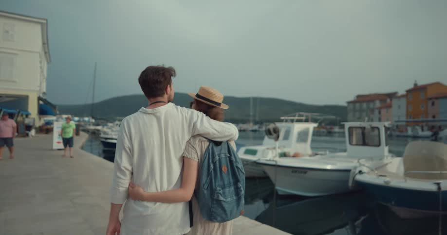 Tourist couple walking holding each other and sightseeing near a lake in a tourist city