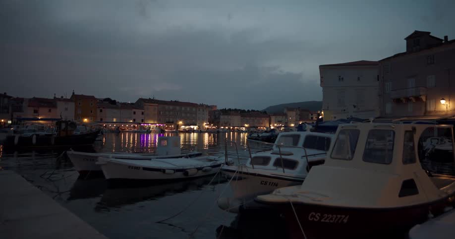 Boats floating on a pier in a small coastal town at evening