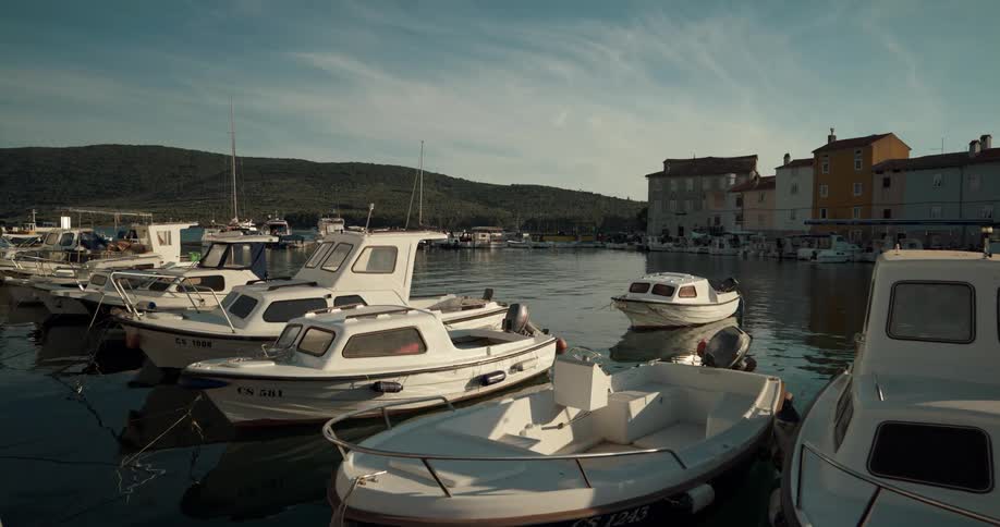 Boats bob in water across from apartment buildings and hills under a cloudy sky