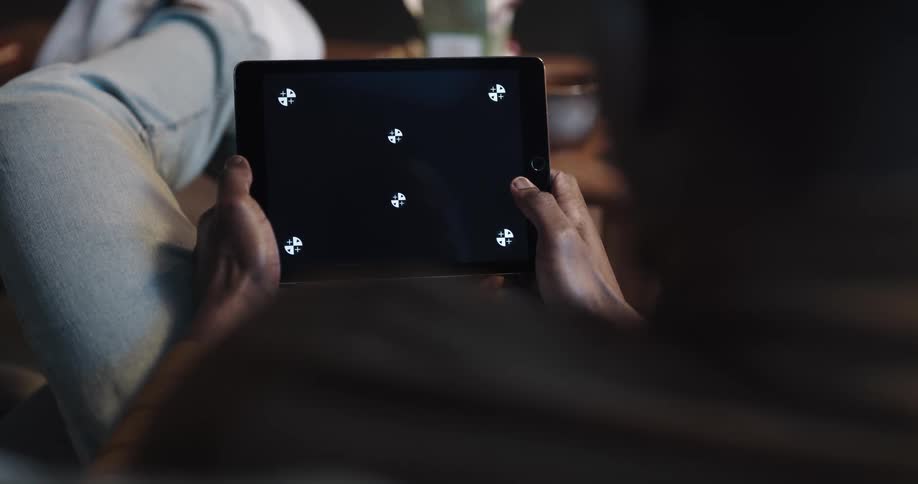 Man laying in the couch on the living room at home uses a tablet with a replaceable screen