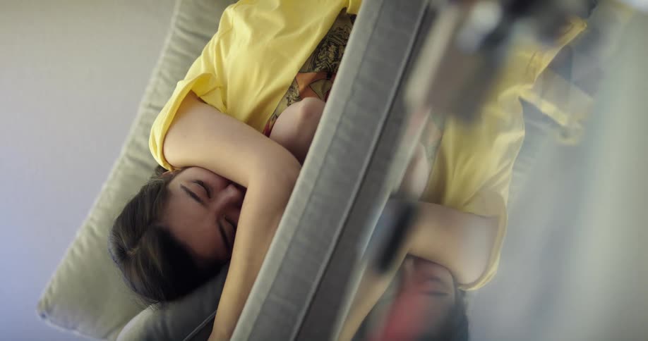 Teenage asian girl putting her smartphone on the table and lying her head on the cushion to take a nap in the couch