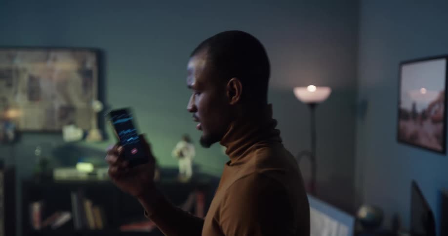Black man standing in his living room talking to the phone