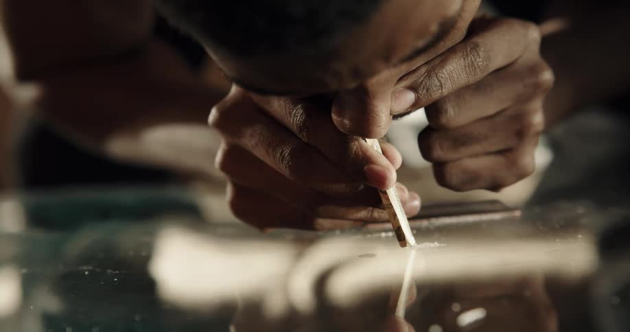 Man snorts cocaine through rolled up paper currency
