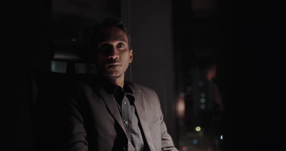 Tired and sleepy man sitting on his office near a big glass window at night
