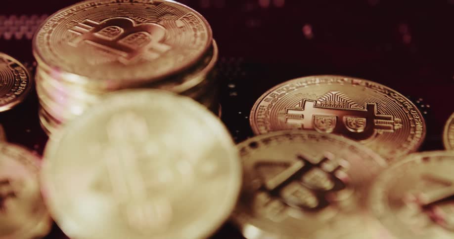 Stacks of gold plated bitcoin coins shimmering in the light