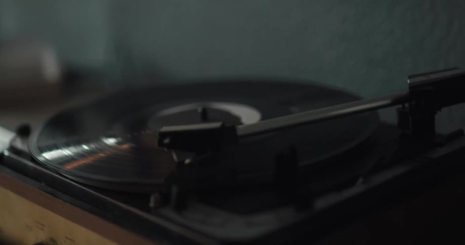 Person placing a vinyl record on a vintage turntable to play