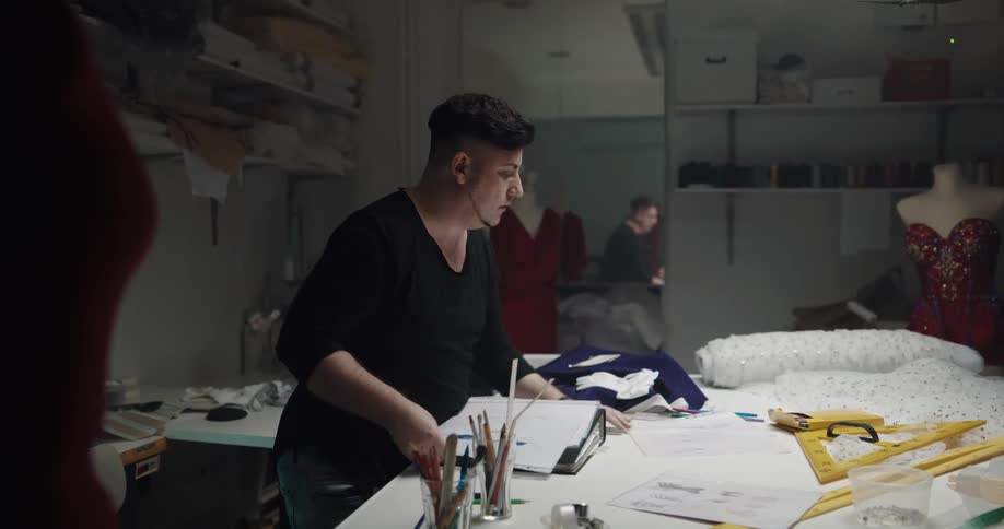 Fashion designer carries a folder with various designs inside his workshop