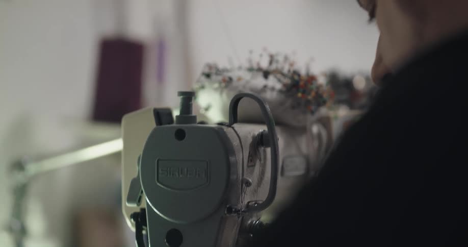 A man retrieves pins from a pin cushion while operating a sewing machine