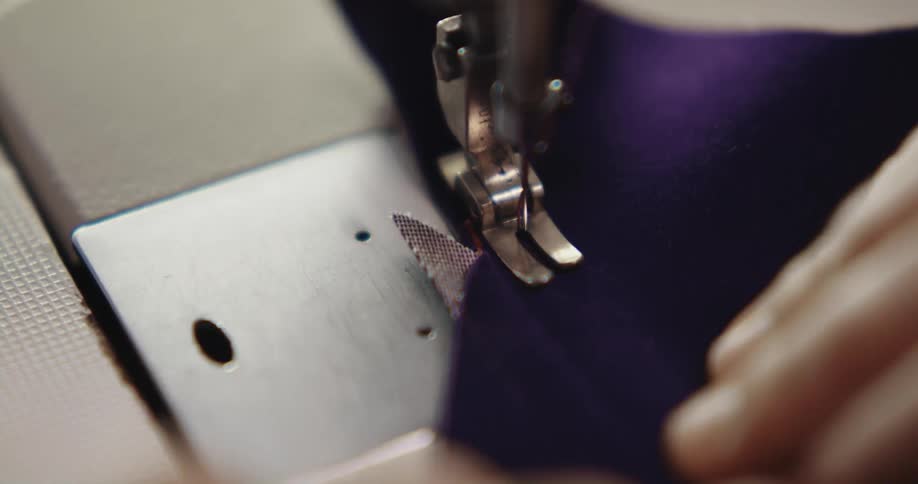 A person positions a piece of fabric under the needle of a sewing machine