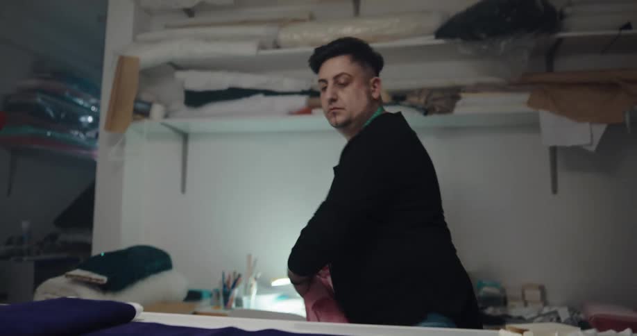 Fashion designer unrolling blue and pink cloth over a table in a workshop
