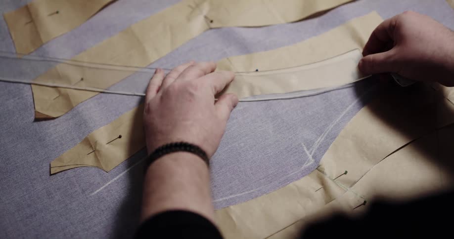 Fashion designer traces patterns over a piece of cloth in his workshop