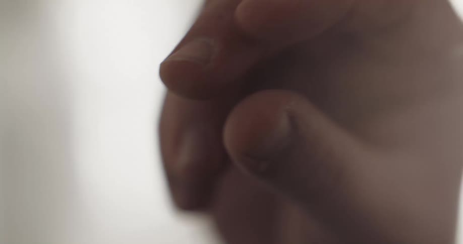 Fingers push white beads on a string