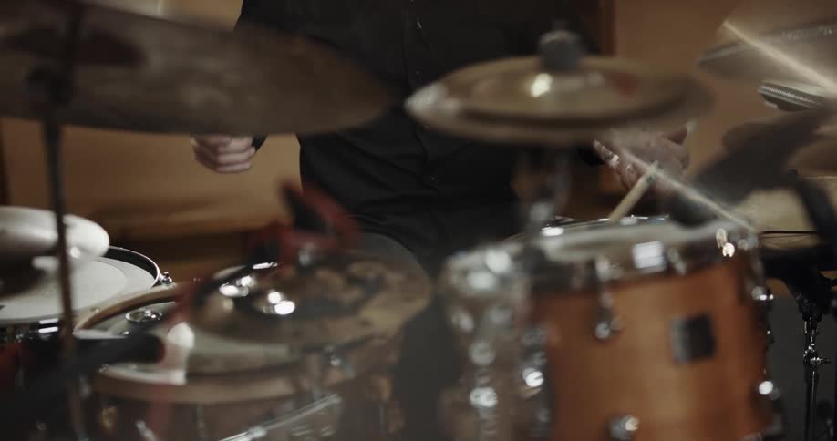 A man sits at a drum set and plays the drums