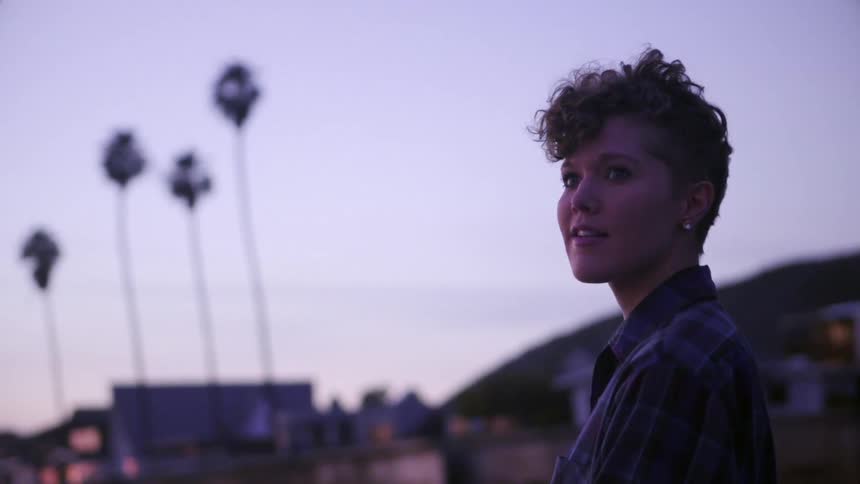 A woman smiles outside at sunset