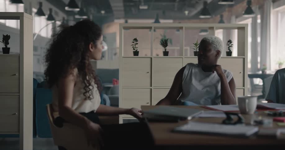 Two women sitting at the table on an office space holding a conversation