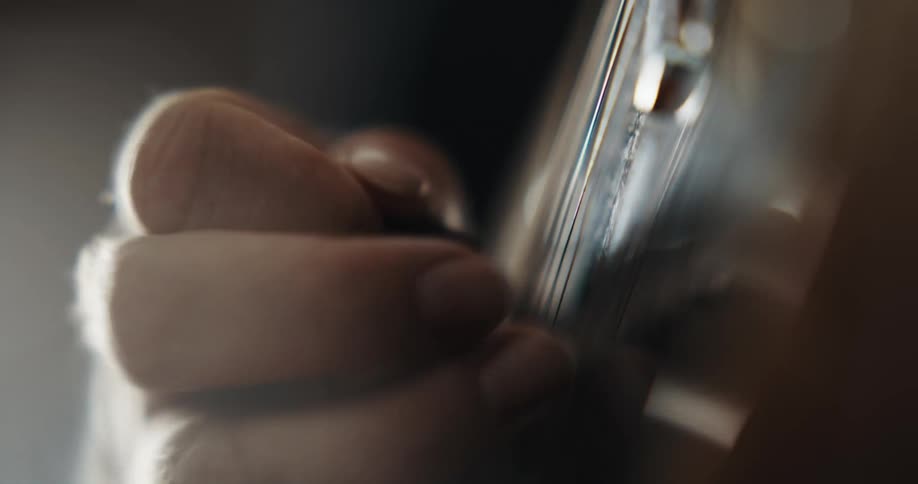 Close up of mans hand playing guitar with plectrum