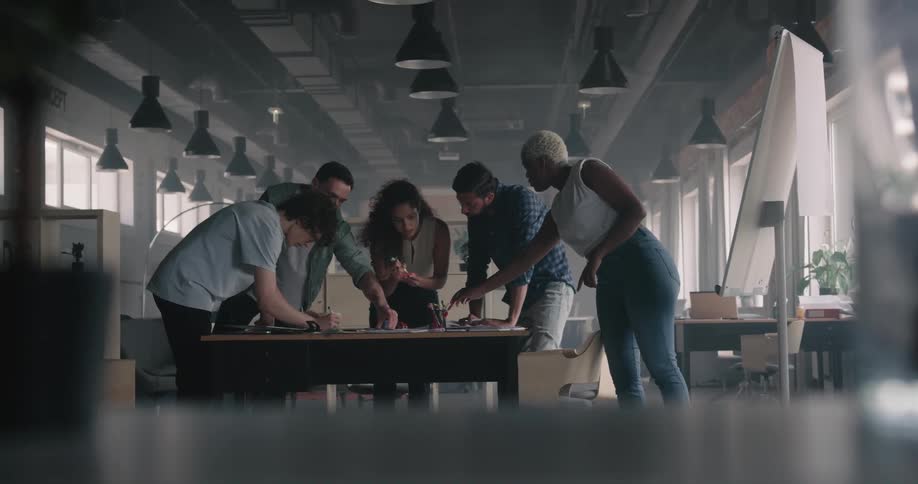 Colleagues brainstorm while standing around a table in the office
