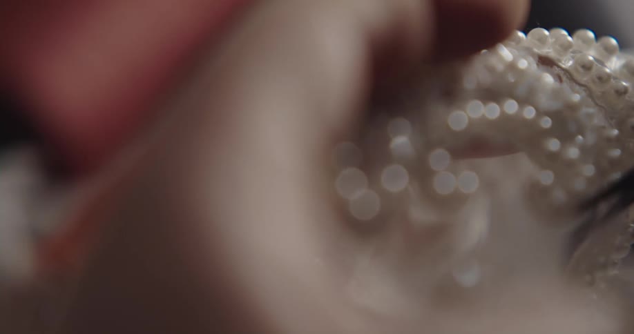 Close up of a person cutting mesh with pearls on it