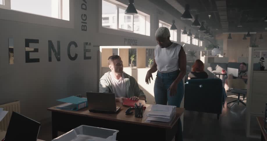 Supervisor walking around the desks at the office talks to employees in the morning