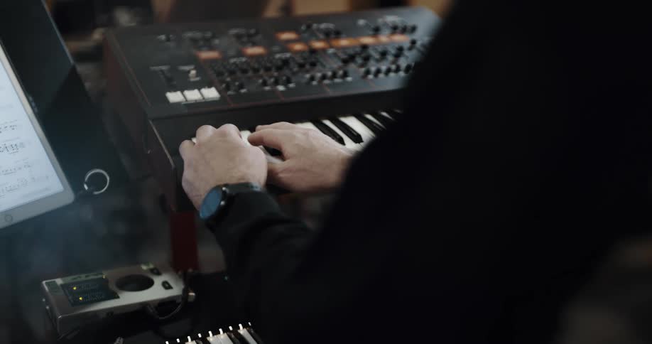 A man plays the keyboard in a recording studio