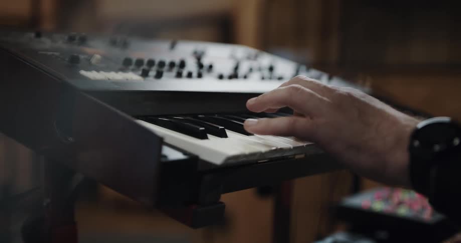 A man plays the keyboard in a recording studio