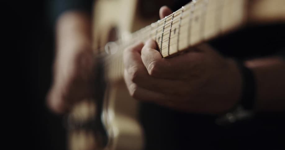 Close up of mans hands playing guitar with fingers