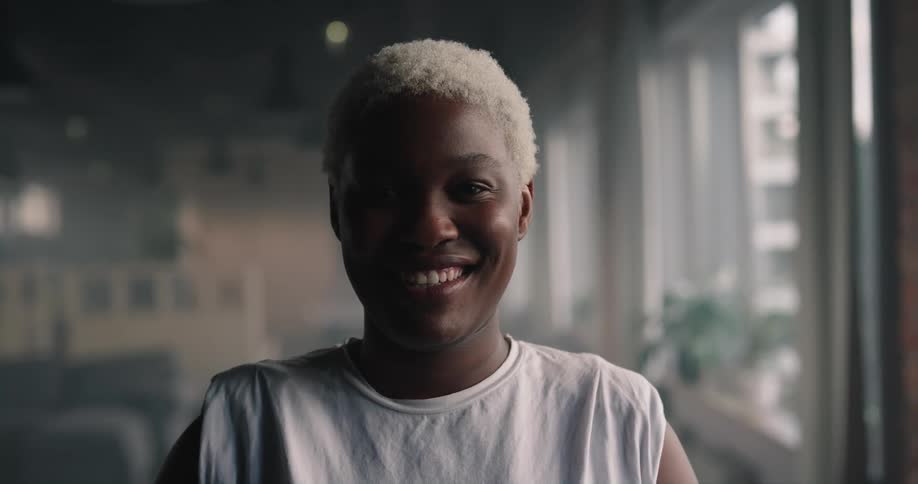 Woman with short fair hair and white t shirt smiles at camera in the office