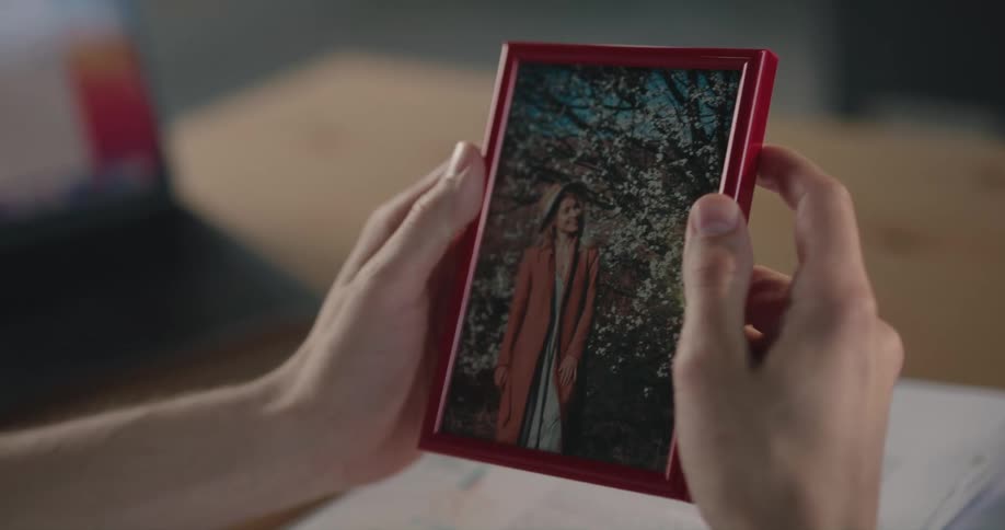 A person picks up a photo of a woman then puts it down face down