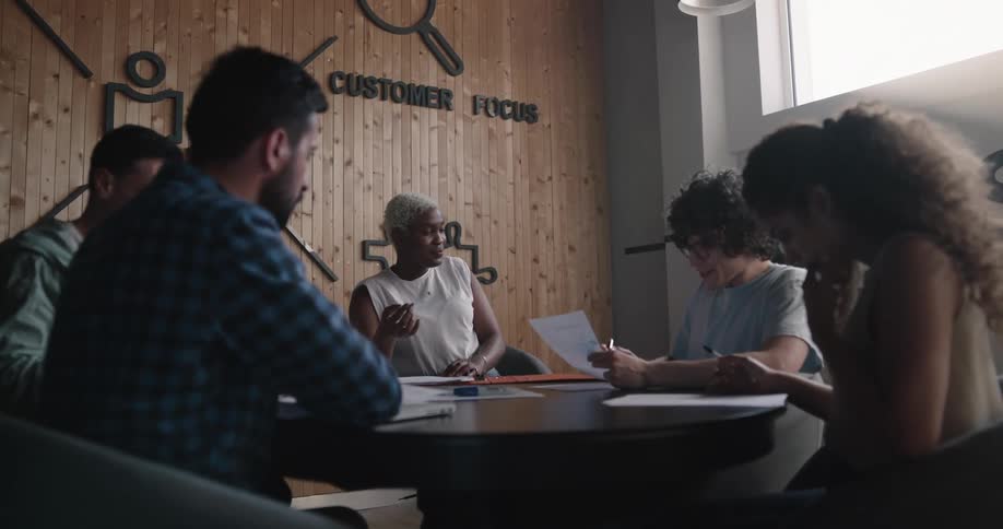 A woman speaks to the people sitting with her around a table at an office meeting