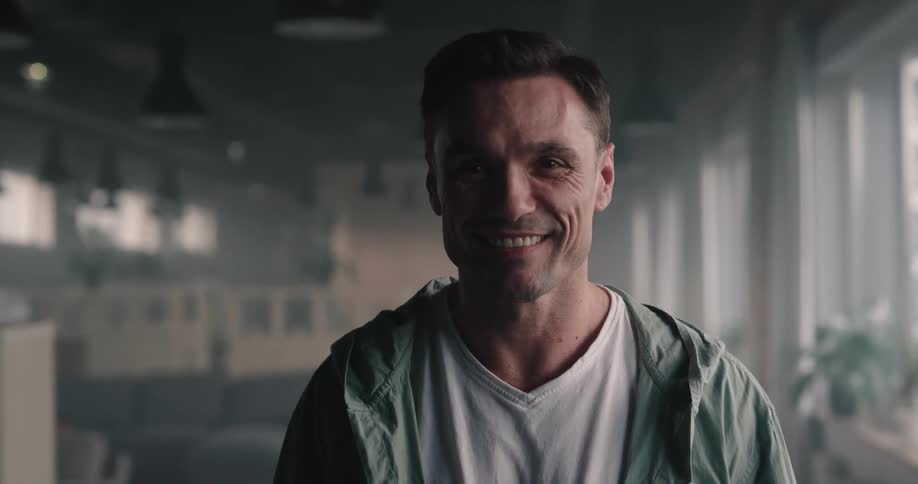 Happy man standing in the middle of an empty office space smiling