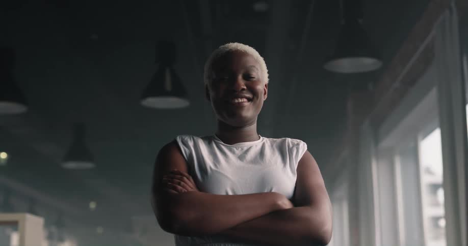 Black woman standing with crossed arms and smiling