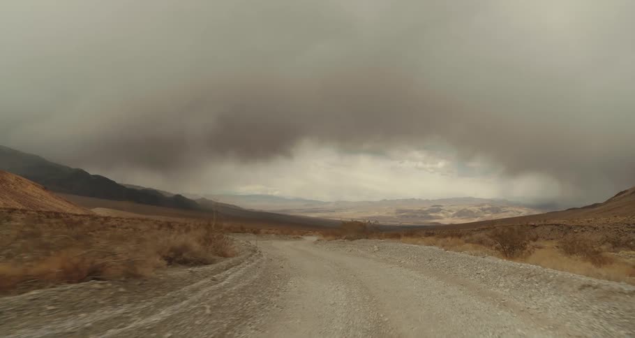 A gravel road through a vast countryside under a cloudy daytime sky