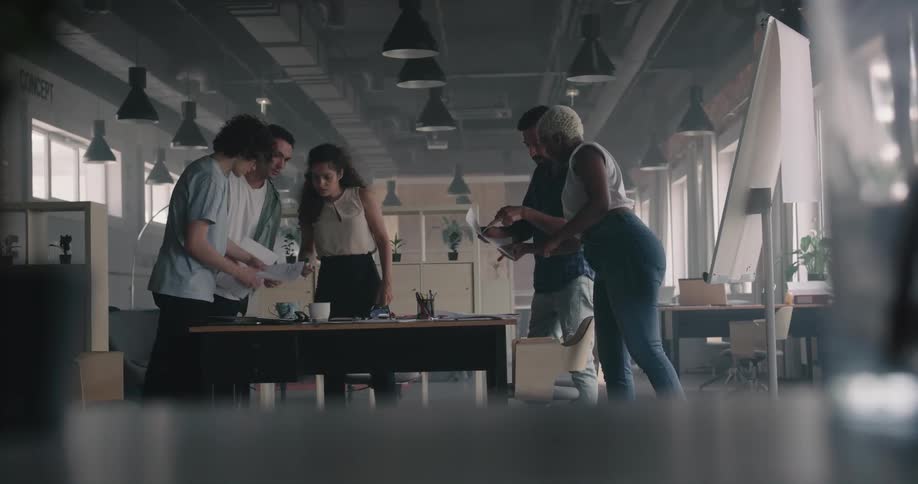 Coworkers stand around table studying and discussing data