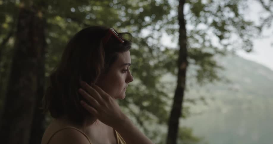 A woman is standing outdoors in a wooded area