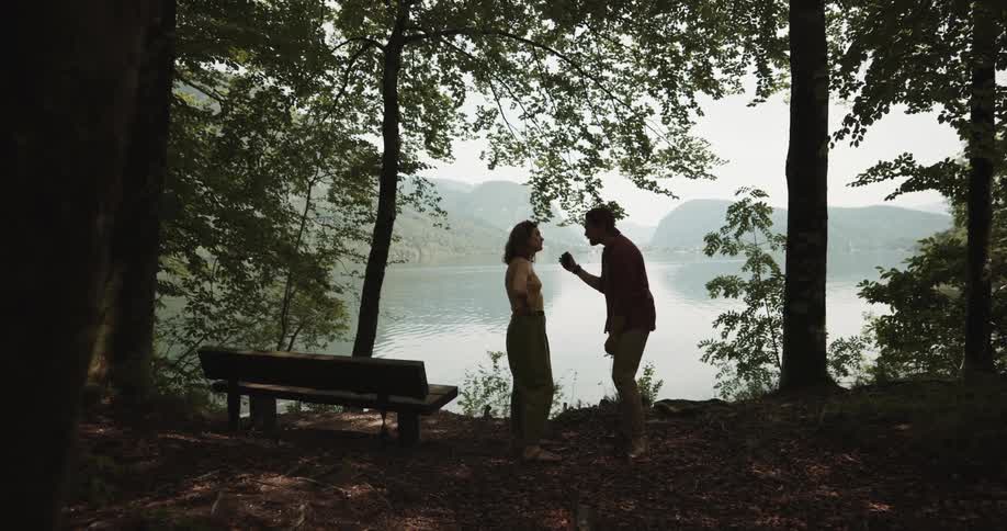 Young couple arguing over a the content of a phone near a lake in the mountains