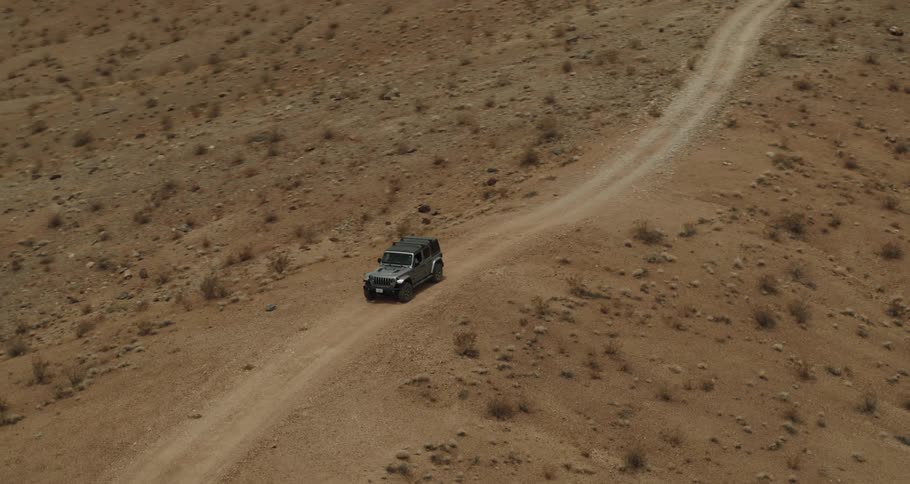 A jeep is traveling on a dirt road through the desert