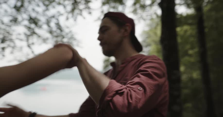 Man trying to hug his girlfriend who is crying and pushing him away near a lake outdoors