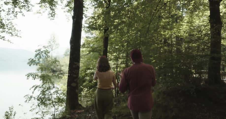 Young couple walking in the forest arguing near a lake in the mountains