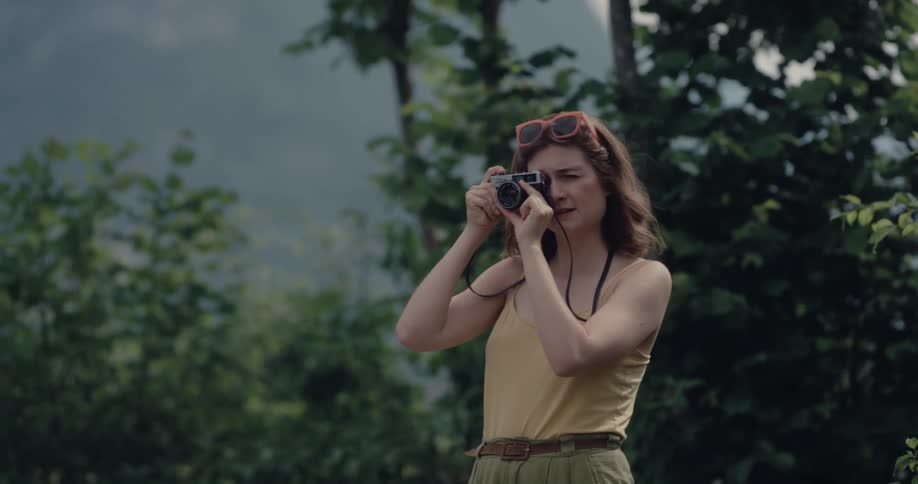 Female photographer stands outdoors taking pictues