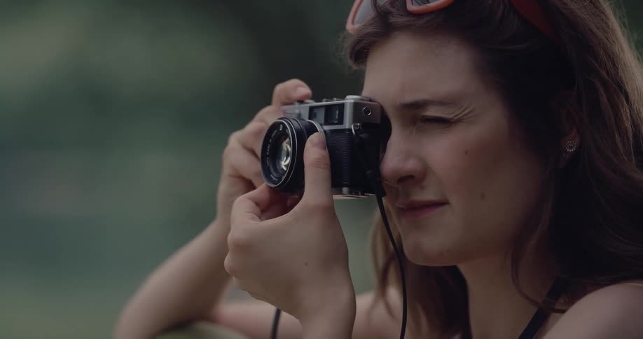 White woman sitting outdoors using her digital camera to take pictures of the surroundings