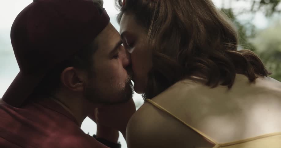 Young couple sitting in front of a lake tenderly kissing and making out
