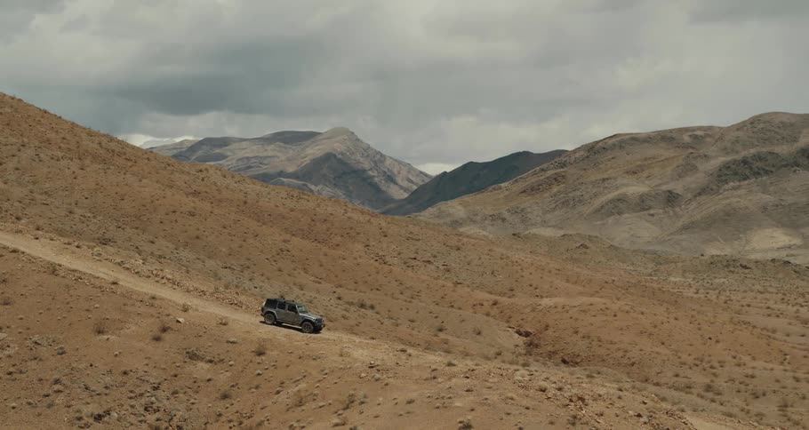 A car is driving through the desert during the daytime
