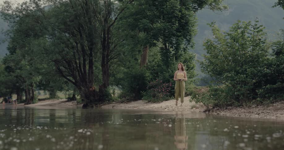 A woman is walking on the coast near the forest