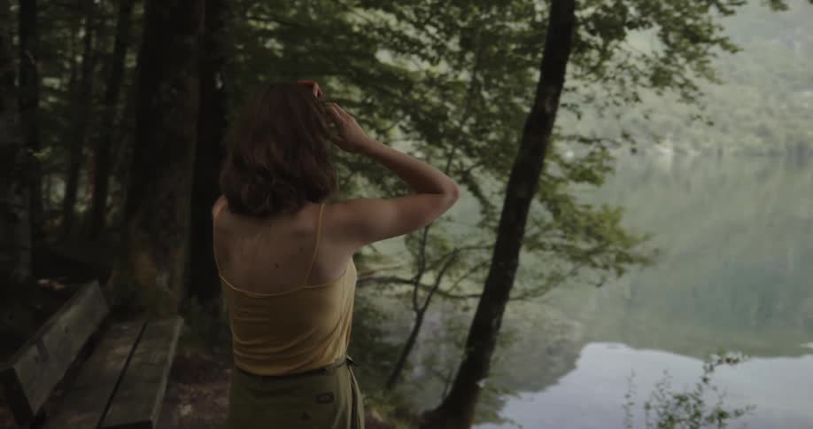 A woman arguing with a man on the shore of a lake slaps the phone out of his hand and shoves him when he tries to reapproach her