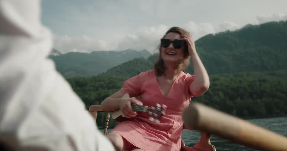 Happy couple on a date in a wooden canoe in the middle of the lake kissing laughing and having fun
