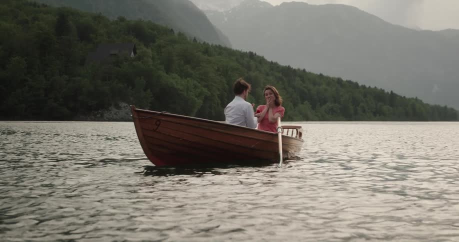 Man proposing to his girlfriend in a wooden canoe in the middle of the lake