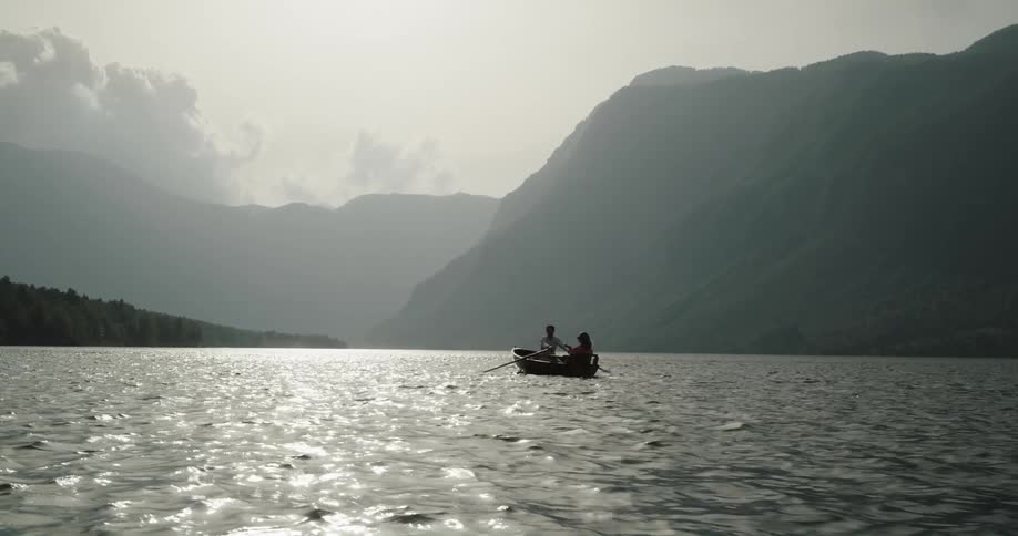 Man and woman on a date in a wooden canoe navigating through a lake