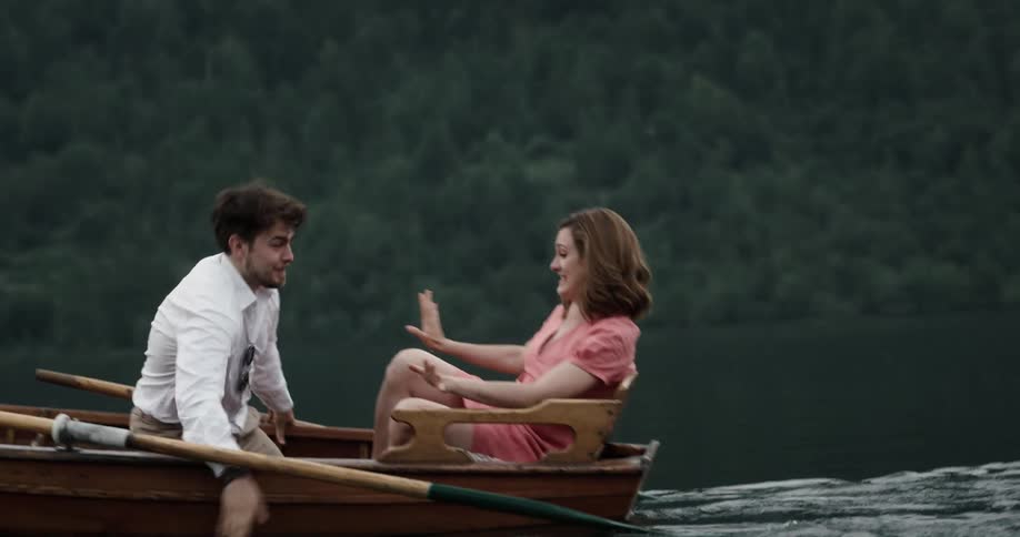 A man stops rowing a boat after getting splashed by his wife to kiss her and splash her back